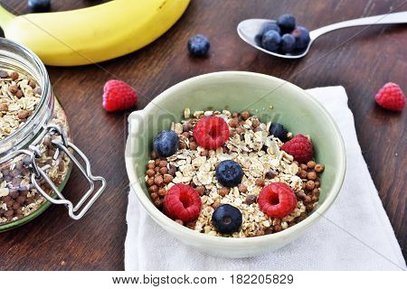 Breakfast bowl with fresh berry fruits. Cereals with blueberries and raspberries on a wooden table.