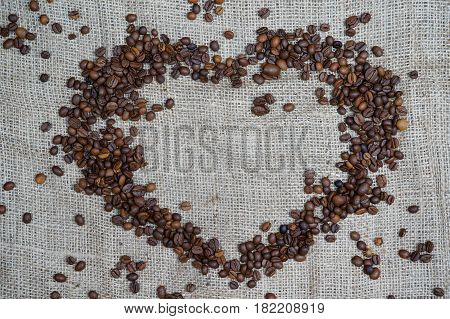 Heart with roasted coffee beans on the burlap background