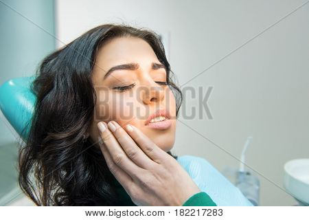 Young woman having toothache. Sad lady at the dentist. Gum disease symptom.