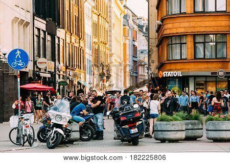 Riga, Latvia - July 2, 2016: Young people meeting and having fun together near parked Motorcycles in the parking lot in Kalku street in sunny summer evening.