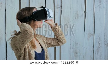 Young woman using Virtual Reality Glasses. Virtual reality mask. VR. White wooden background. Future and technology concept