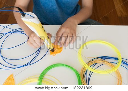 Kid's hands with 3D printing pen. Top view