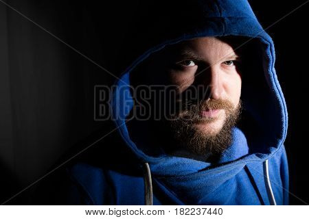 Solid bearded middle-aged man in a hood  portrait on black background