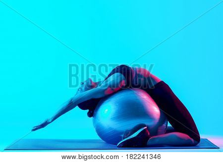 one mixed races woman exercsing fitness pilates exercices isolated on blue blackground