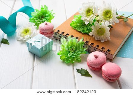 beautiful chrysanthemum flowers notes and macarons on a white wooden table