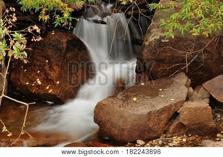 Waterfall cascading slowly over rocks in forest