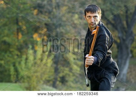 Ninja in black kimono with kusarigama is outdoors.