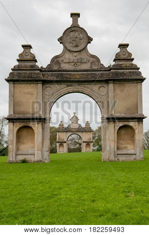 Stone Monument With Two Arches In A Formal English Garden