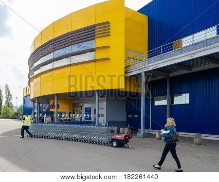 PARIS FRANCE - APR 10 2017: Woman walking in front of the Ikea furniture store looking at the emplyee pushing multiple shopping carts for customers