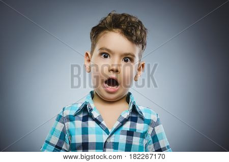 Closeup Portrait of handsome boy with astonished expression while standing against grey background.