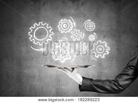 Butler holding metal tray with teamwork concept against concrete background