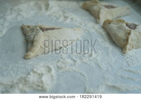 Already wrepped ground meat with hole. Baking peremech concept. Flour, dough and meat cooking ingredients. Hands top view of cooking belyash cuisines.
