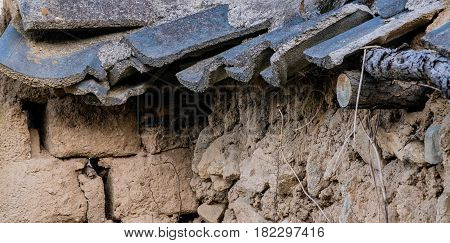 Closeup of a mud brick wall with black tile roof fallen into state of disrepair in South Korea