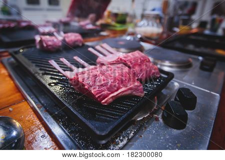 Different stages of cooking the steak on a kitchen, barbeque, roasted lamb ribs, big dish plate with roasted full pork head, served in restaurant with vegetables, lamb, ham and chicken.