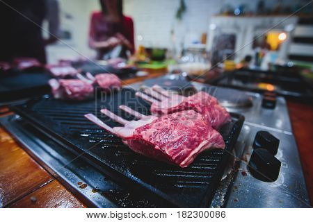 Different stages of cooking the steak on a kitchen, barbeque, roasted lamb ribs, big dish plate with roasted full pork head, served in restaurant with vegetables, lamb, ham and chicken.