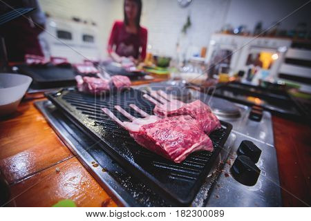 Different stages of cooking the steak on a kitchen, barbeque, roasted lamb ribs, big dish plate with roasted full pork head, served in restaurant with vegetables, lamb, ham and chicken.
