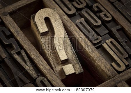 question mark - vintage wooden letterpress type block in old typesetter drawer among other letters, sepia toned black and white image