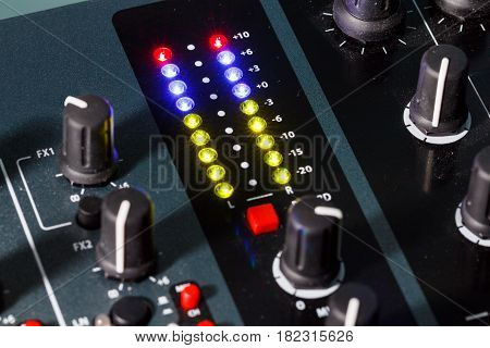 Close up shot of a DJ mixer volume faders with volume levels in the red