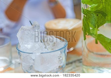 Glasses with ice cubes on wooden table in cafe