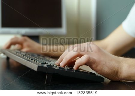 Image of male hands typing on computer keyboard