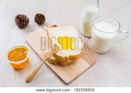 Breakfast with milk sliced bread and jam on the wooden table