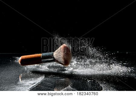 Makeup brusk and powder on black background with copy space