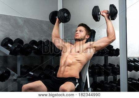 Handsome young sportsman wearing shorts exercising at the gym with heavy weights copyspace lifestyle activity energy effort ambitions power strengthen concept.
