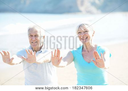 Senior couple doing stretching exercices on the beach