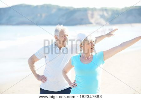 Senior couple doing stretching exercices on the beach