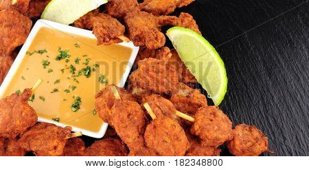 Chicken satay skewers with peanut sauce dip on a slate background