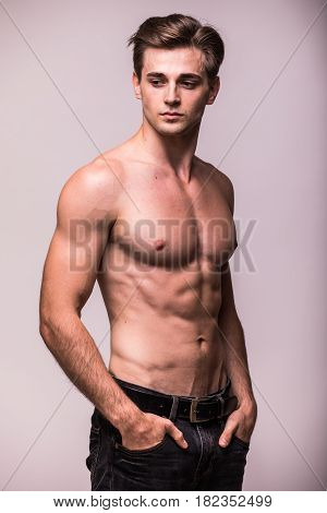 Portrait Of Bare Muscular Torso Of Young Man On Grey