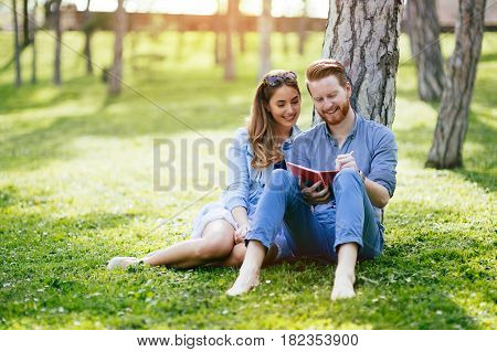 Beautiful couple studying together for exams in nature