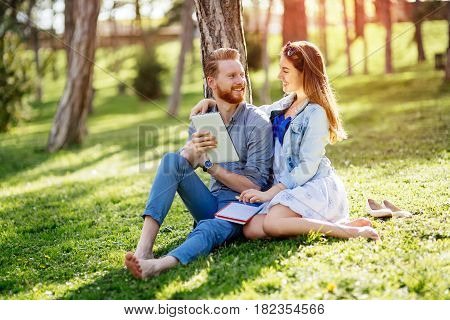 Beautiful couple studying together for exams in nature