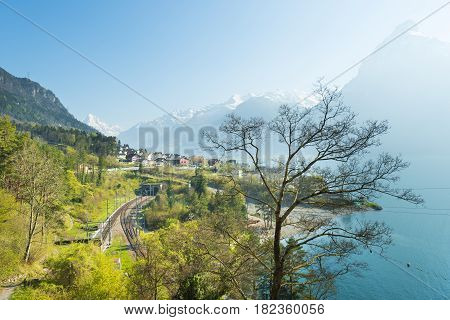 View of the small town in the Alps mountains. Traditional houses. Railway along Lake Lucerne. Canton of Uri.
