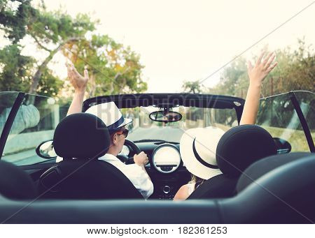 Happy free couple in car driving in car cheering joyful with raised arms