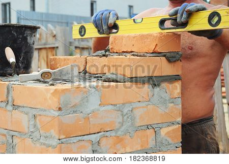 Bricklayer Bricklaying Concept. Bricklaying Tools. A bricklayer using a level to check his new house construction wall outdoor. Brickwork. Bricklaying Bricklayer Brickwork.