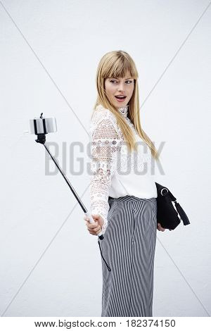 Gorgeous blond model posing with selfie stick