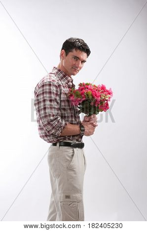 The adorable man is holding some flowers.