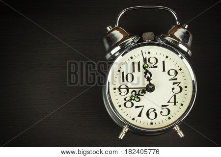Retro metal alarm clock on a black wooden background. Open your eyes. Reveille to wake up. Place for text