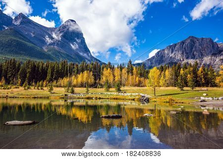 The shallow lake among the woods and mountains.  Shining day in Canmore, Canadian Rockies. Concept of autotourism and hiking
