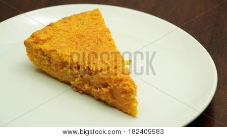 Slice of carrot cake on white plate on wooden background