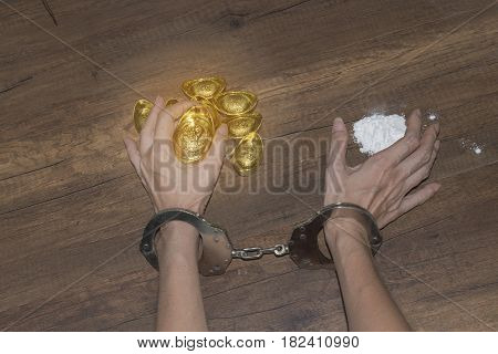 The chrome metal handcuffed bondage on man hand during holding gold bar represent the crime fraud and punishment equipment concept related idea. Addictive substance no freedom Translation in English meaning lucky and richly