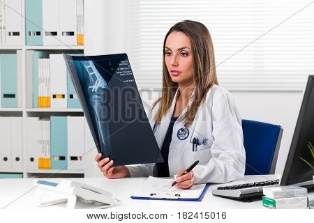 Female Doctor Looking At Patients X-ray In Her Office
