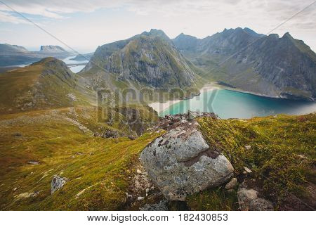 Beautiful Vibrant Norwegian Mountain Landscape from Ryten peak - famous mountain in Lofoten Islands, Moskenes municipality, Nordland with a view of Kvalvika beach, with hiking tourists and blue sky