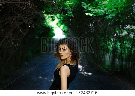 Portrait of a girl in a black shirt. Summer. Green trees.