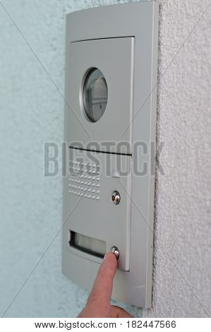 Person presses on door intercom with camera - closeup