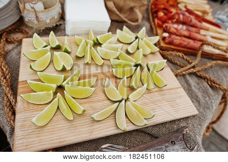 Cutted Into Slices Lime On Wood Board At Wedding Catering Table.