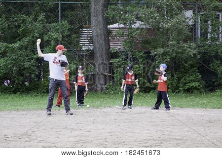 Montreal, Quebec - May 18, 2015 -- Wide view of little league baseball players practicing with their coaches in a park in Montreal, Quebec on a bright day in May.