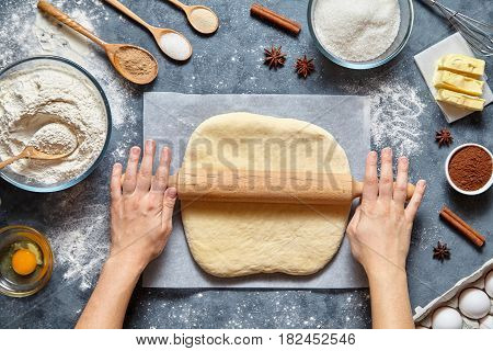Dough bread, pizza or pie recipe traditional preparation. Female chef cook hands rolling dough with pin. Food ingridients flat lay on kitchen table. Working with pastry or bakery cooking. Top view