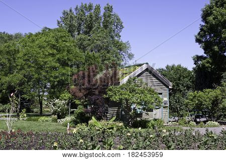 Laval, Quebec - June 14, 2015 - Landscape view of a small wooden garden house surrounded by trees foliage and a small garden in the Nature Park, Laval, Quebec on a sunny day in June.